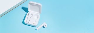 White Xiaomi Mi true wireless earphones 2 earbuds resting in it's white case on a blue background