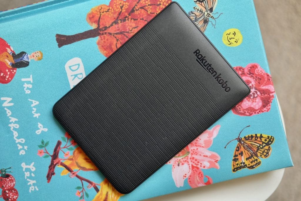 A black Kobo e-reader placed upside down on a notebook, back panel view