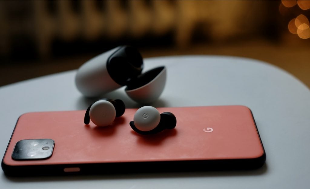 White-black Pixel buds resting on a Pixel smartphone laid on a table