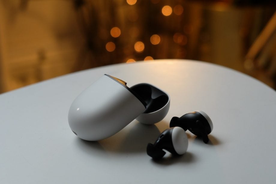 White-black Pixel buds resting beside their case on a white table