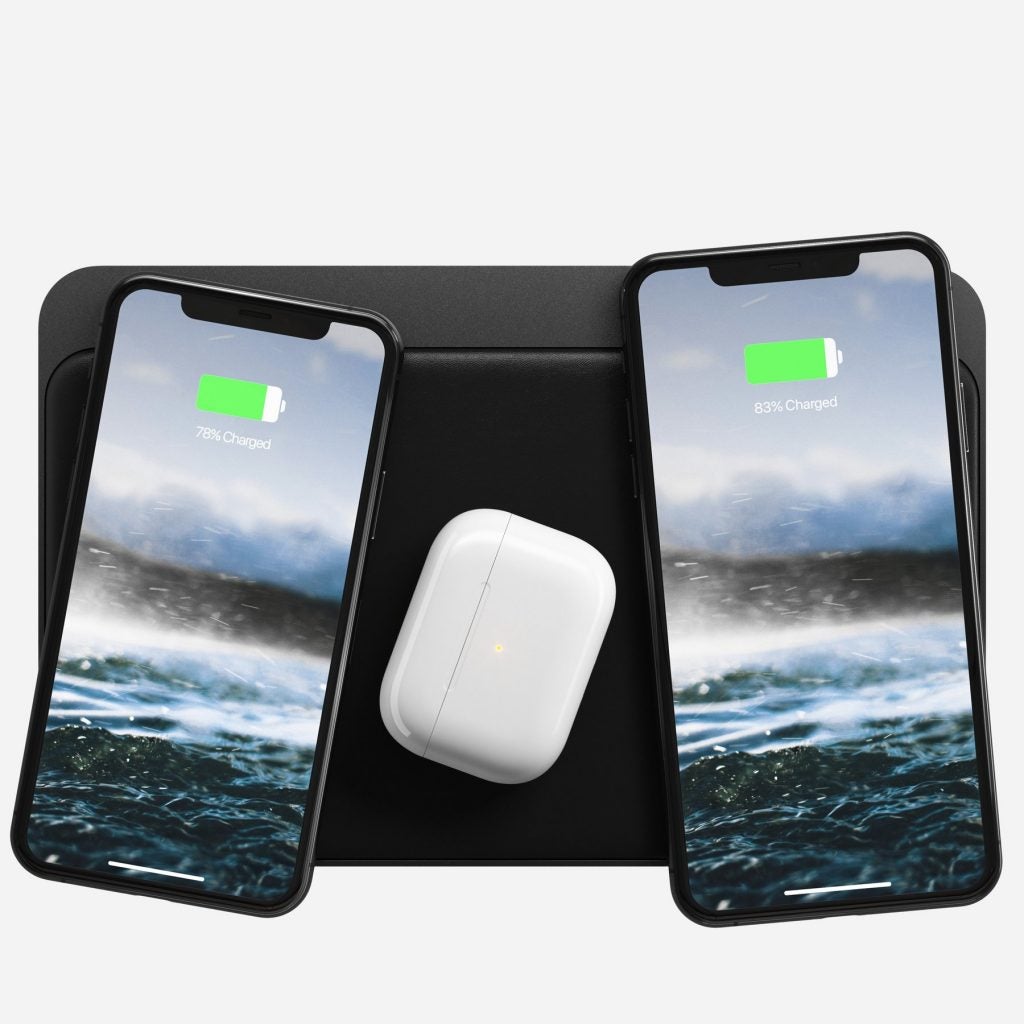 Two iPhones and AirPods resting on a Magsafe standing on a white background