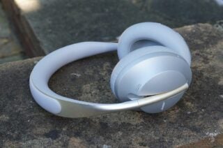 Silver-white Bose NC 700 heaphones resting on cemented ground