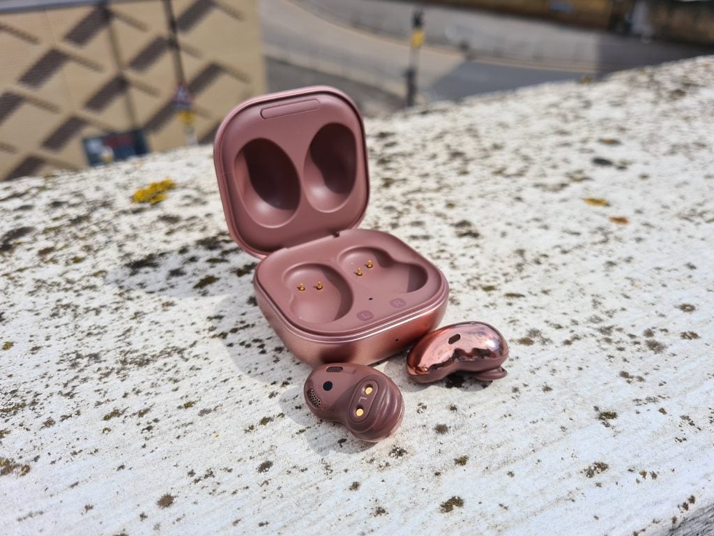 Samsung Galaxy Buds LiveBrown Galaxy Buds Live earbuds resting on a concrete floor with it's case standing behind