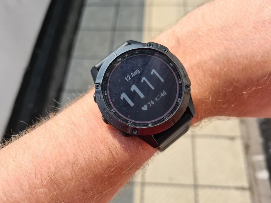 A black Garmin Fenix 6 Pro watch tied on wrist displaying date and time