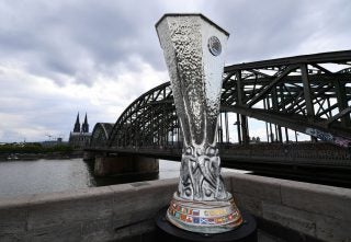 A silver trophy standing on a platform with a black bridge behind it