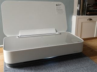 A white HP Tango X printer resting on a wooden table with it's scanner's lid open