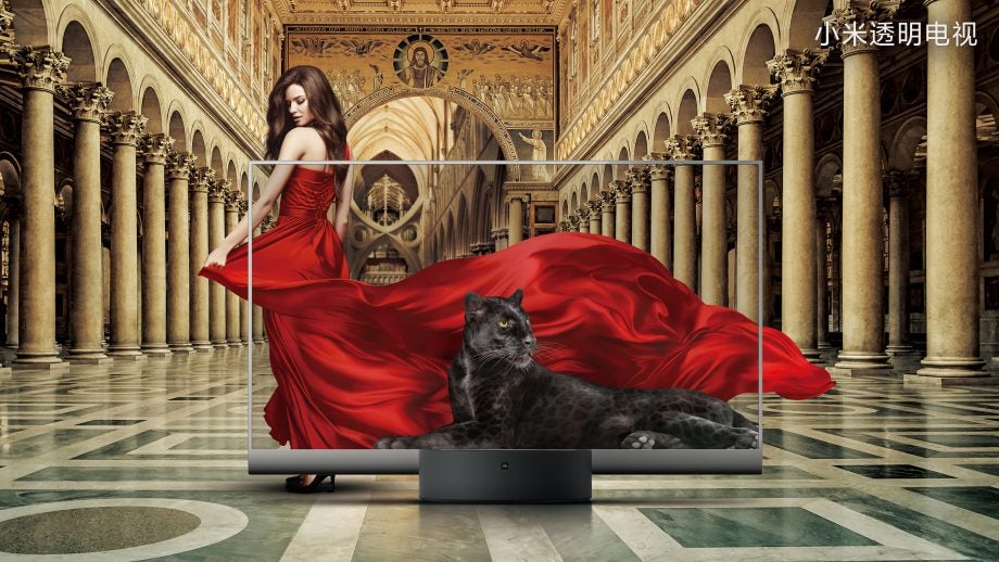 A black Mi TV LUX OLED transparent edition, displaying a cat sitting and a girl in red outfit walking behind
