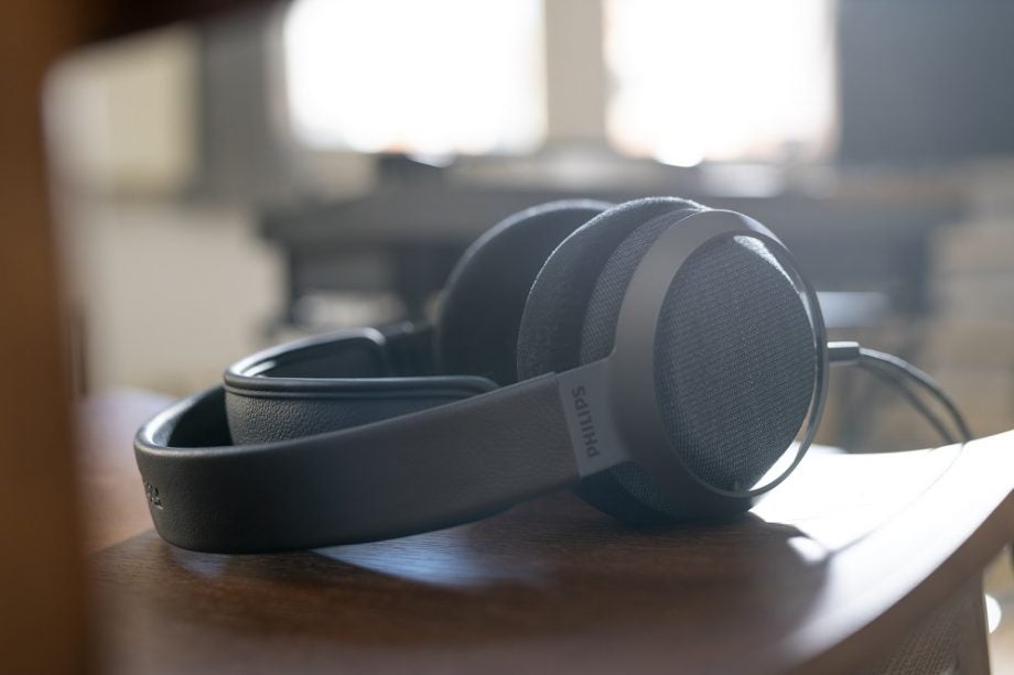 Left angled view of gray Philips X3 headphones laid on a wooden table