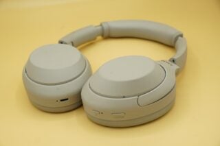 Sony WH-1000XM4 noise-canceling headphones on yellow background.