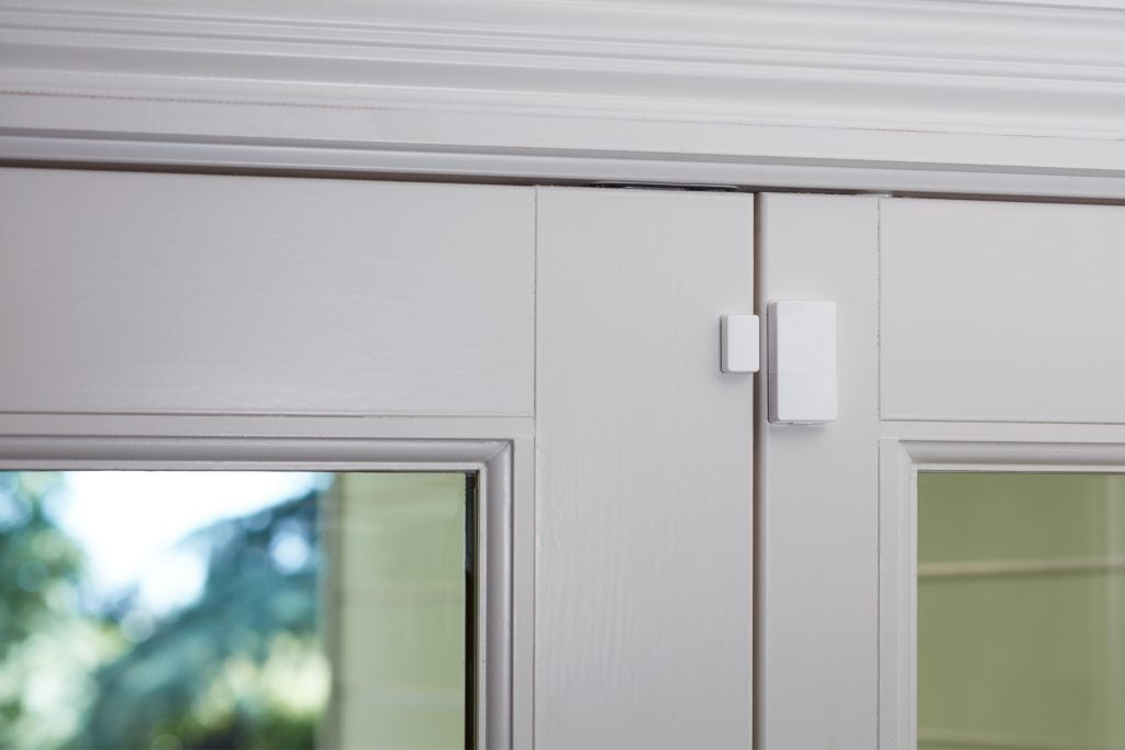 A white Abode mini door sensor attached to the door