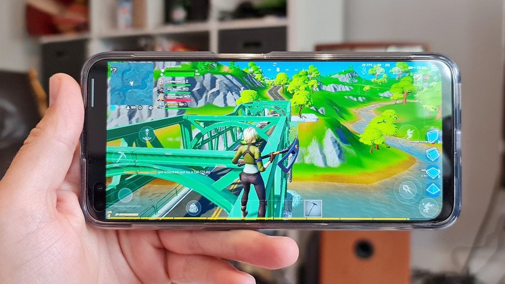 A smartphone held in hand horizontally displaying a scene from Fortnite game