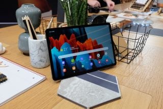 A black Samsung Galaxy Tab S7 standing on a table displaying home screen