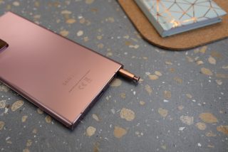 A brownish-pink Samsung Galaxy Note 20 Ultra laid upside down with S-Pen half pulled out