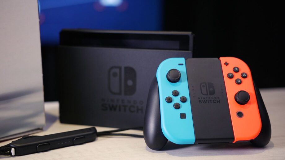A blue, black, and orange Nintendo switch standing on a wooden table
