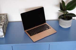 Left angled view of a brownish-golden Macbook Air standing on a blue table