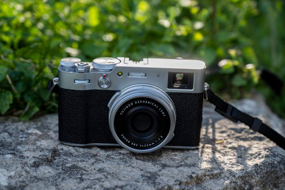 Front view of a black Fujifilm X100V standing on a concrete block