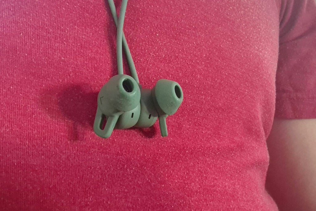 Close up image of green Huawei Freelace Pro earphones hanging on a guy
