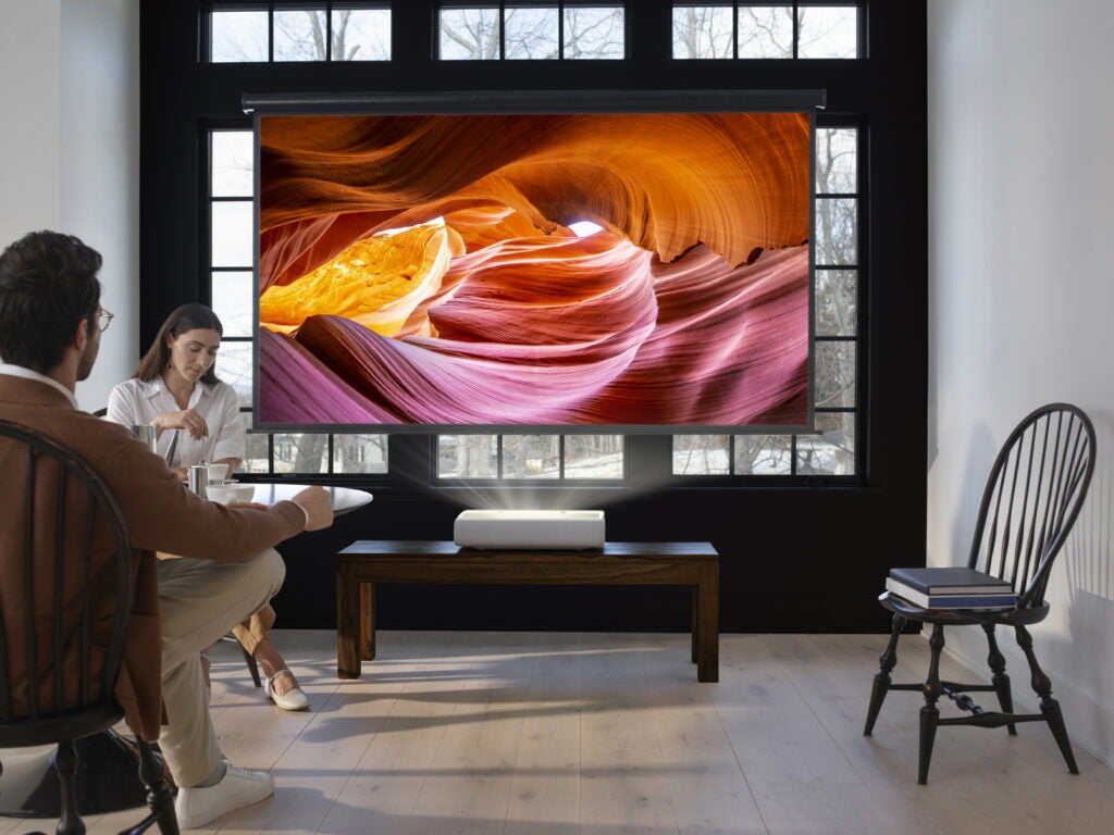 Picture of a couple sitting on a round table with projector displaying a wallpaper on projection screen