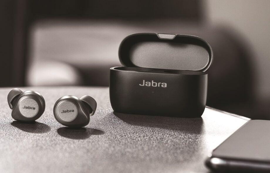 Black and white image of Jabra earbuds resting on a table with it's case resting beside