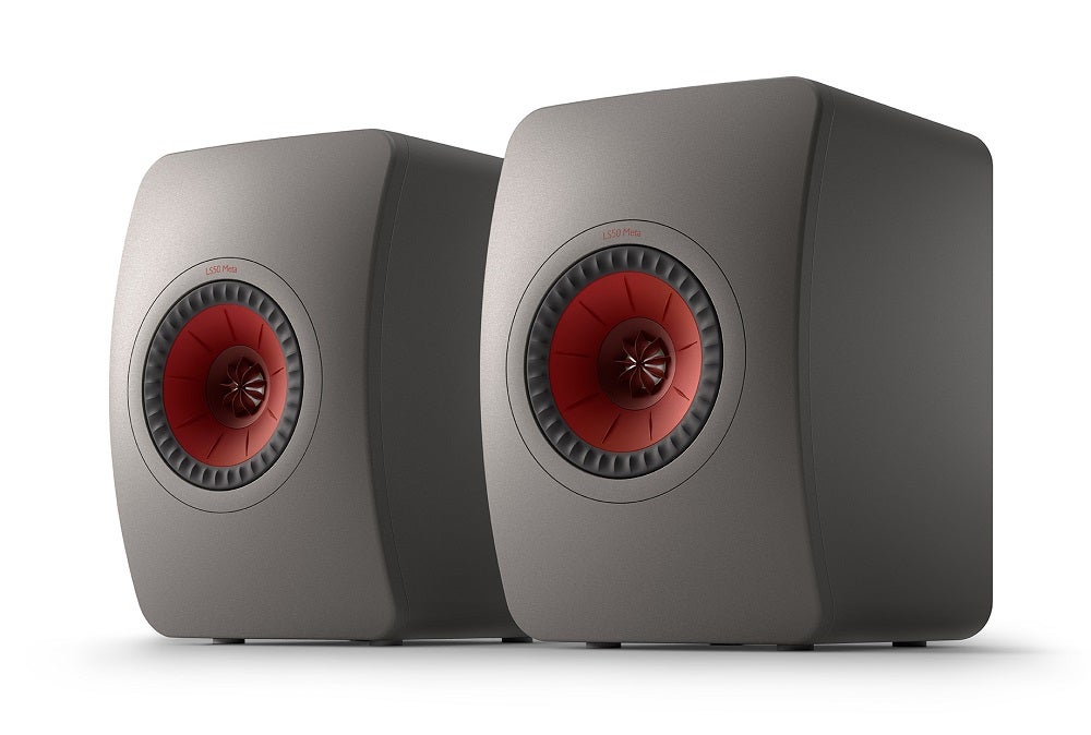 Right angled view of two creamish brown KEF LS50 speakers standing on a white background