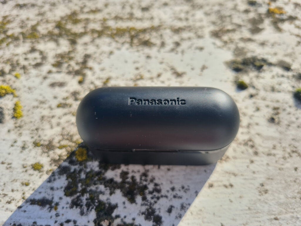 Black Panasonic SW500 earbud's black case standing on a floor