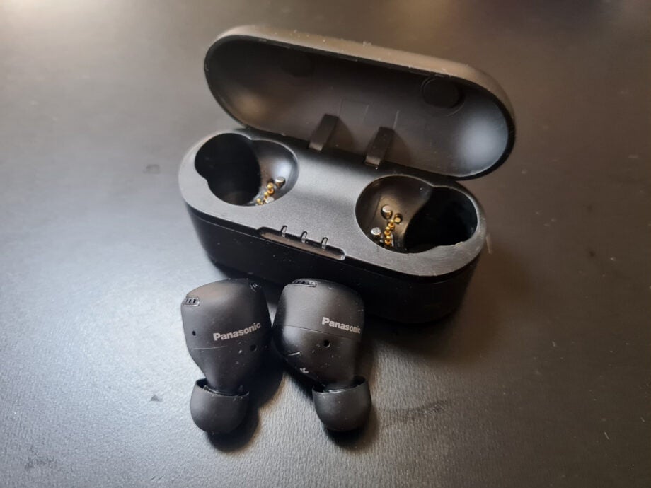 Black Panasonic SW500 earbuds resting on a table with it's case resting beside
