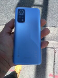 A blue Xiaomi Apollo held in hand facing back , back panel view