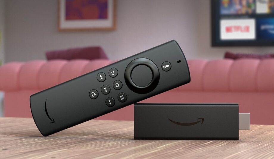 A black Fire TV stick lite laid on a wooden table with it's remote leaning on it