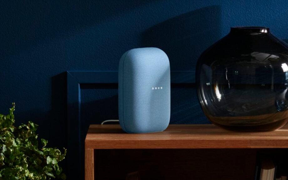 A blue Google Nest Audio speaker standing on a wooden table