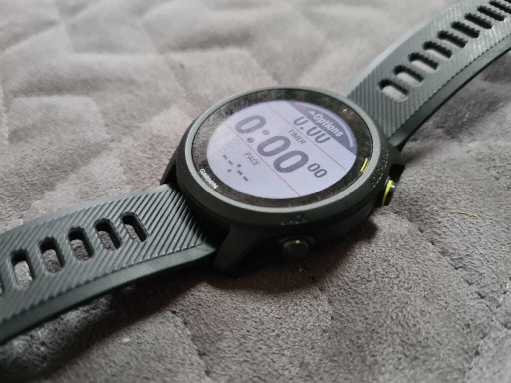 Right angled view of a black-green watch displaying timer laid on soft surface