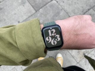 A watch tied to a wrist with big printed numbers, view from top