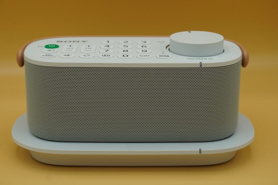 Side view of a white Sony wireless handy TV speaker standing on a wooden table