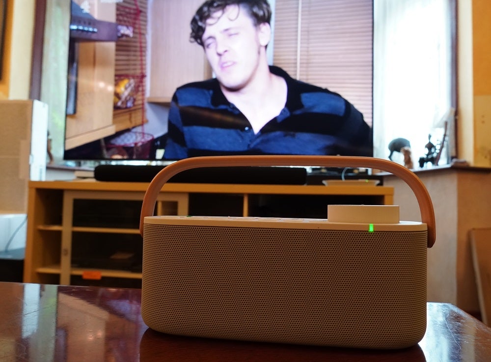 A white Sony wireless handy TV speaker standing on a wooden table