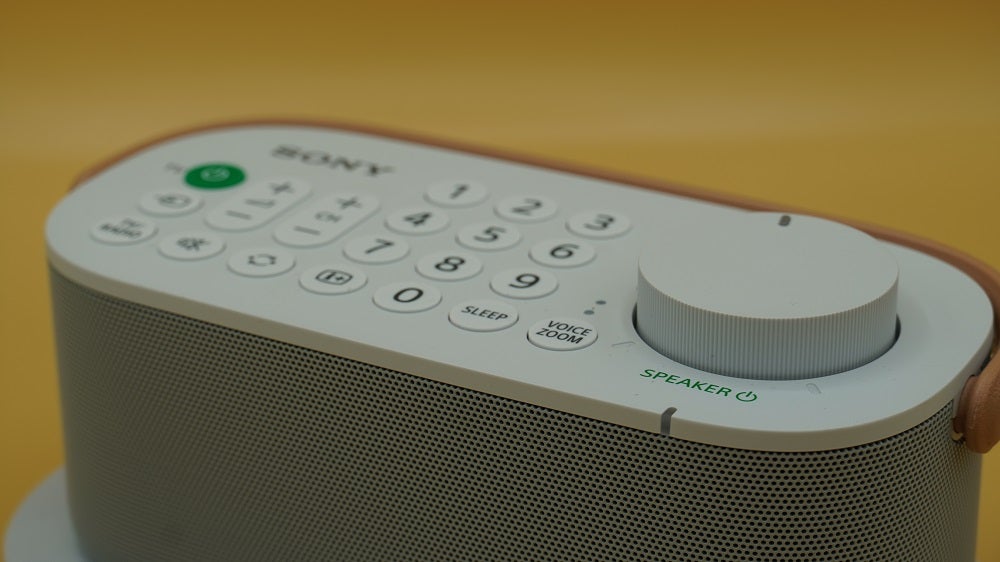 Close up image of a white Sony wireless handy TV speaker's buttons section
