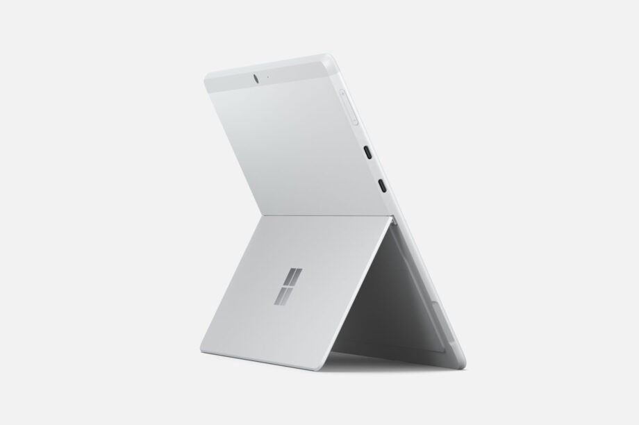 Back right view of a white-silver Surface Pro X laptop standing on a white background