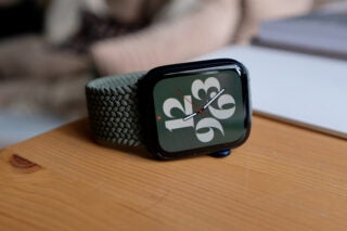 A green-black watch laid vertically on a wooden table