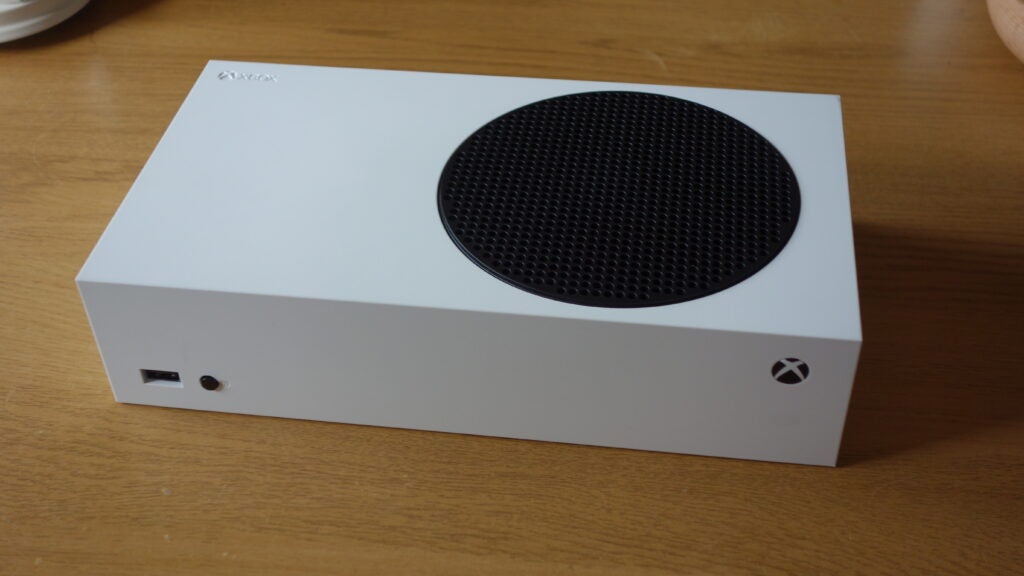 Вид справа на белый Xbox, лежащий на деревянном столе