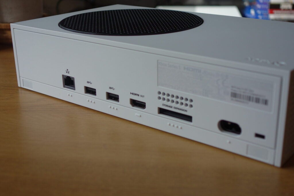Xbox Series SLeft side edge view of a white Xbox resting on a wooden table, close up view of ports section