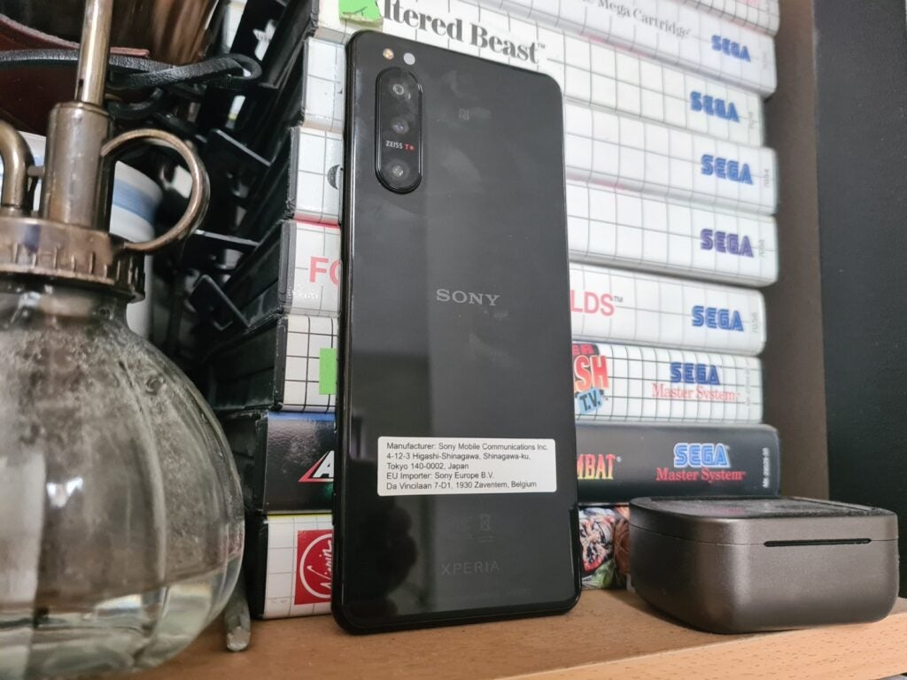 A black Xperia 5 II smartphone standing against a shelf of book facing back