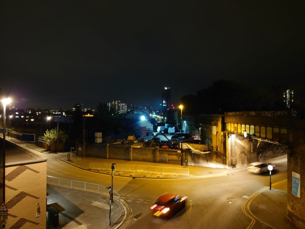 View from top, of a street with a underbridge on the right and houses and warehouses all around, night timeView from top of a street with underbridge on the right and houses and warehouses around