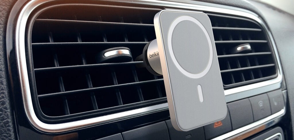 A silver-white Belkin magnetic vent attached vertically to the car AC