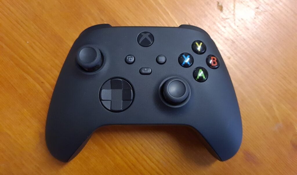 View from top, of a black Xbox controller resting on a wooden table