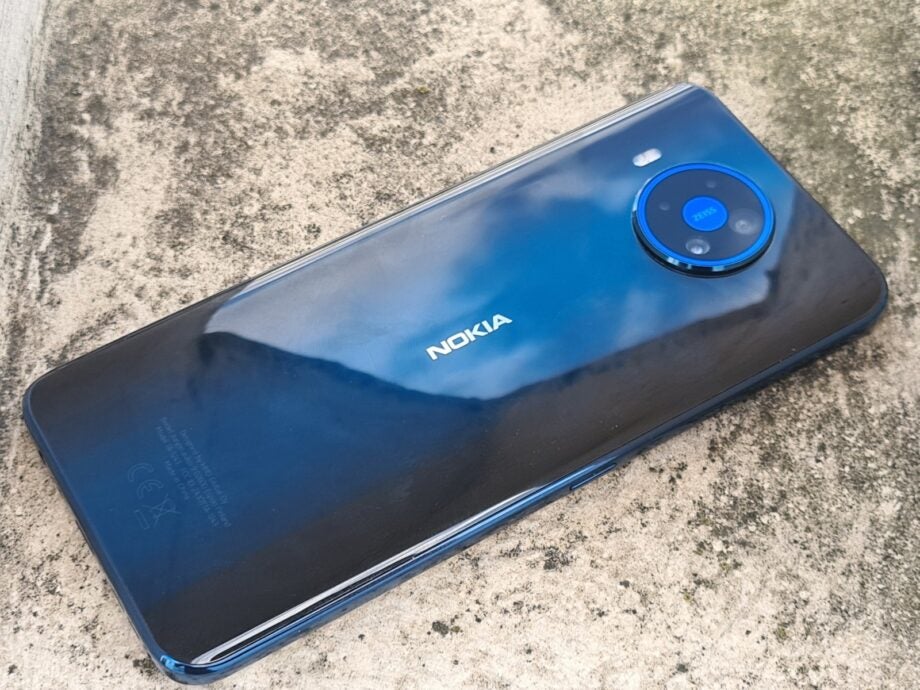 A blue Nokia smartphone laid facing upside down on a concrete block