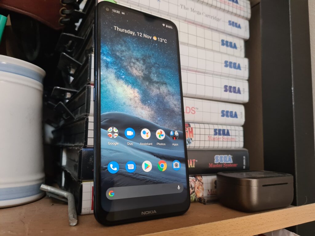 A black Nokia smartphone standing against books placed one over the other, displaying home screen