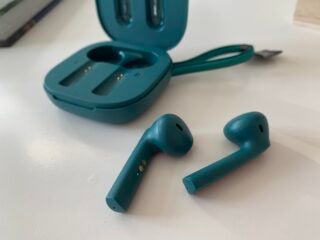 Green earbuds resting on a white background with its case resting behind