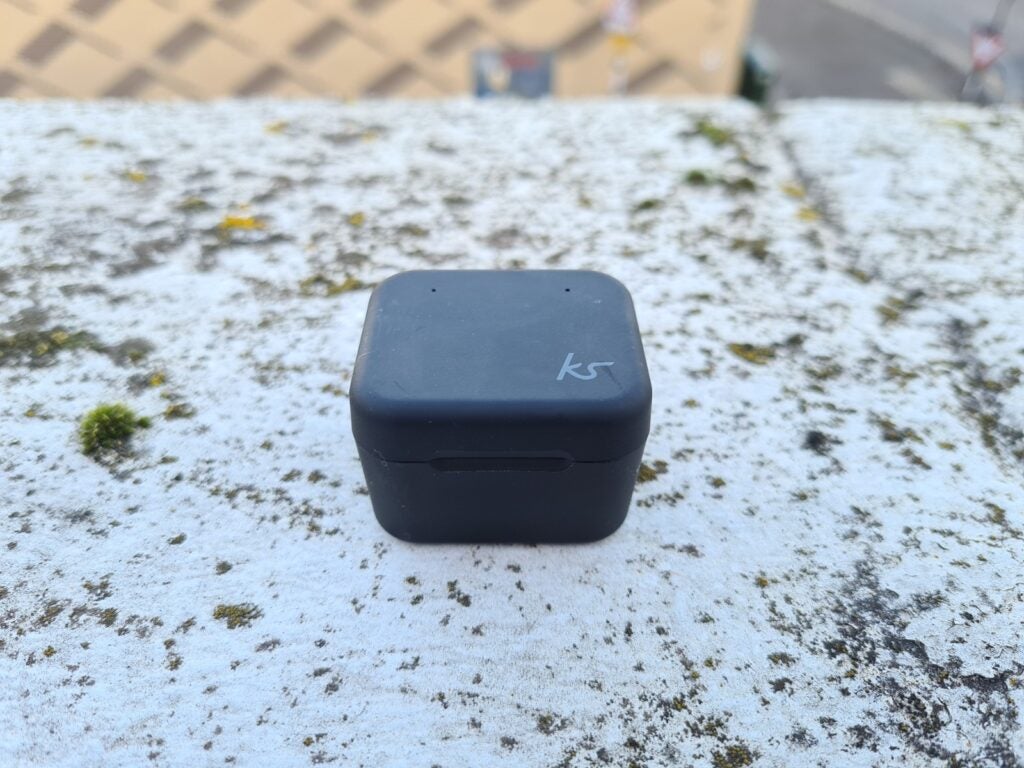 Front top side view of Kitsound Funk 35 earbud's black case standing on a concrete block