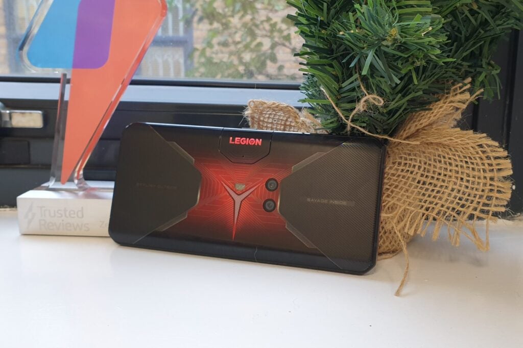 A red-black Lenovo Legion Duel standing horizontally against a plant, facing back