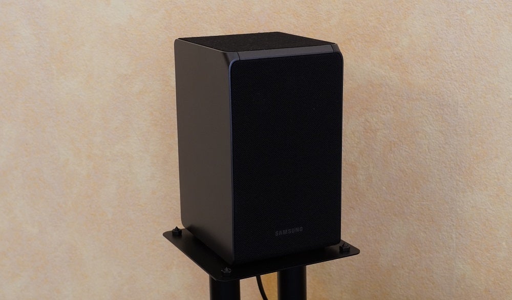 A black speaker from the set of Samsung HW Q950T speaker standing on stand