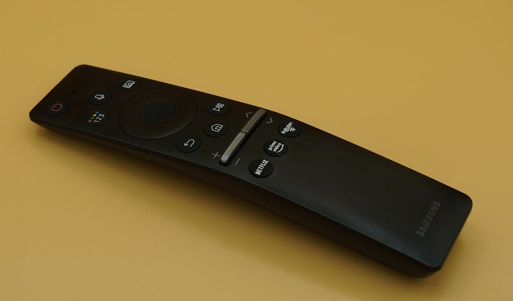 Samsung Q80T's black remote laid on a yellow background