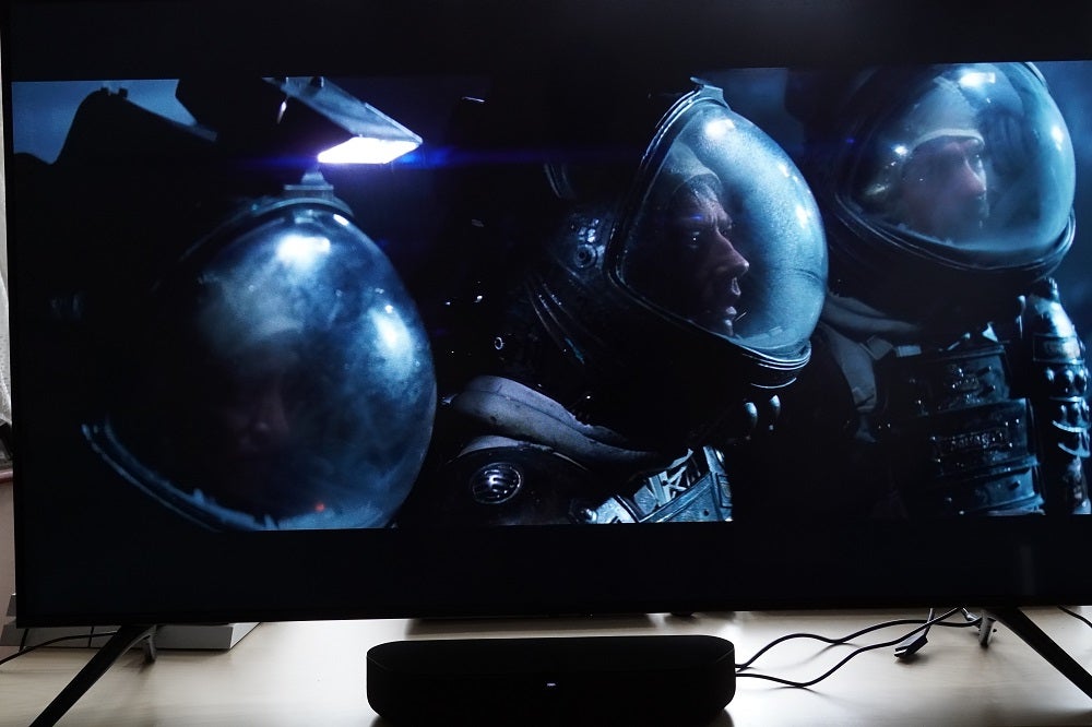 A black Samsung UE50TU7020 TV standing on a table, displaying a scene from Aliens